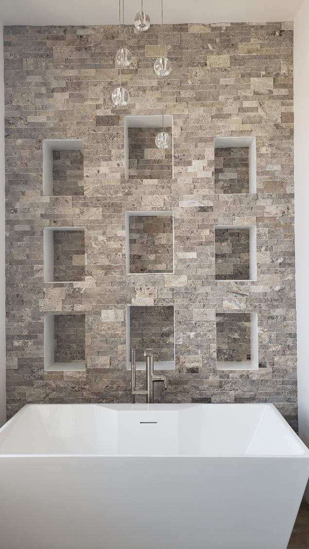 Stacked stone bathroom accent wall with tile niches behind a freestanding tub in Wenatchee WA